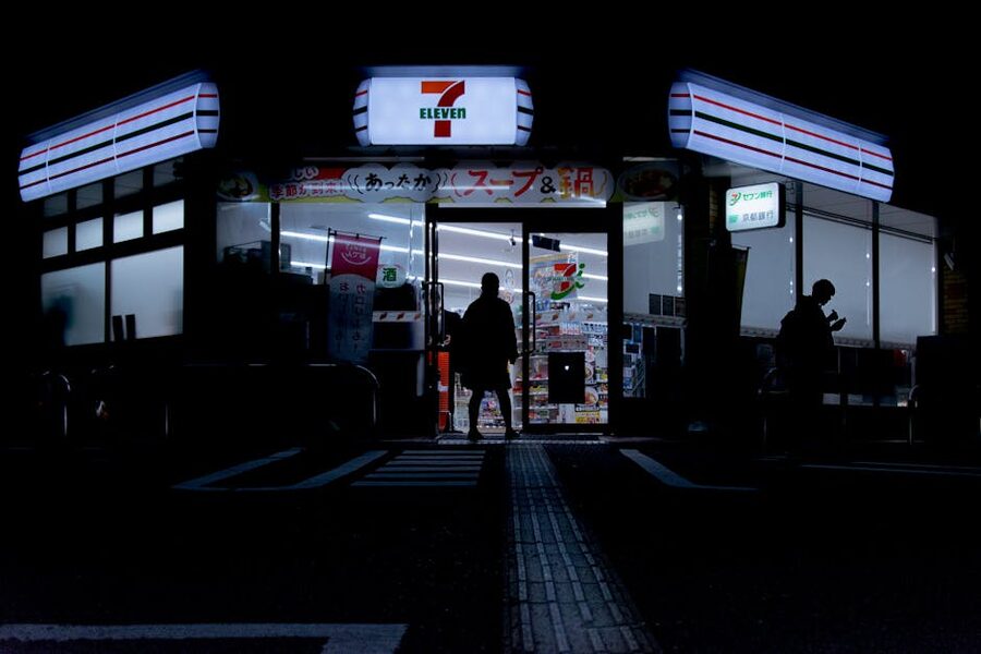 People walking into a 7-Eleven at night in Tokyo