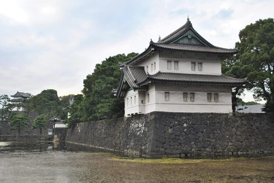 Tokyo Imperial Palace moat with stone walls and white tower