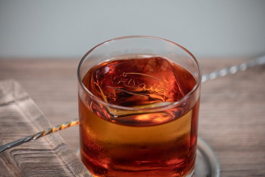 Whisky highball glass with ice on wooden bar surface
