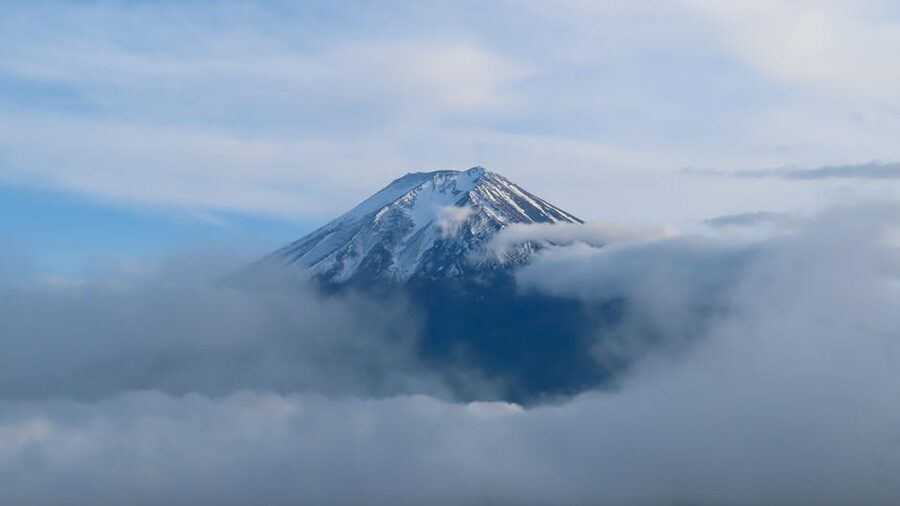 Mount Fuji snow-capped peak with clouds and clear blue sky