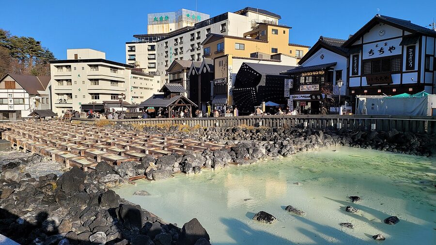 Wooden troughs at Kusatsu Yubatake cooling hot spring water during the day