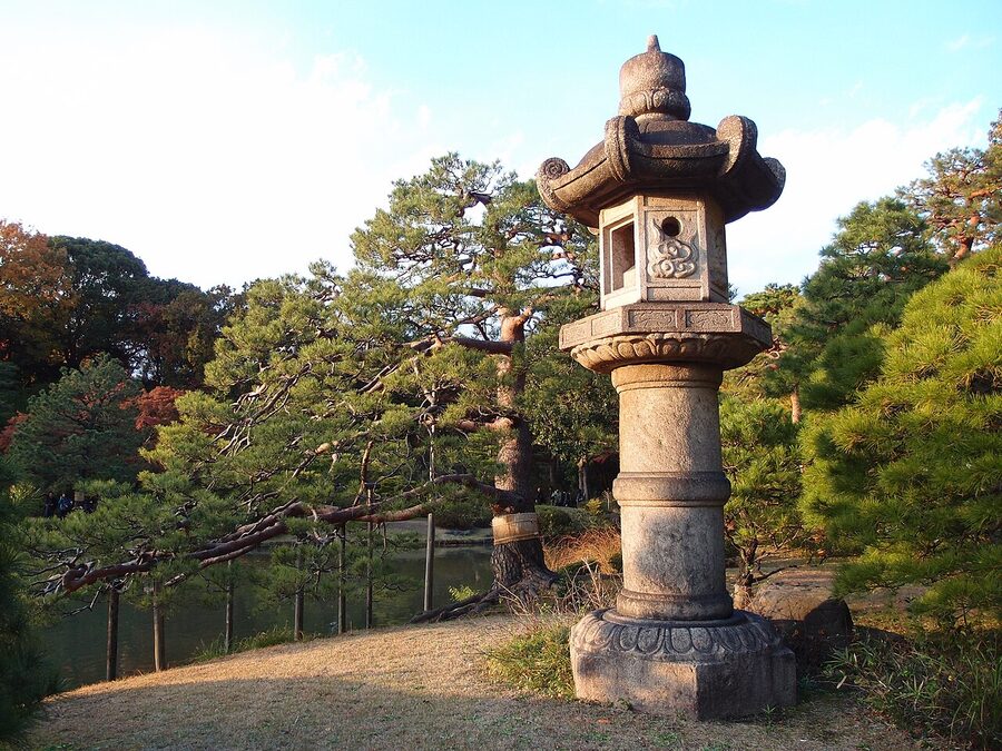 Stone toro lantern on the pond edge in autumn at Rikugien, Tokyo