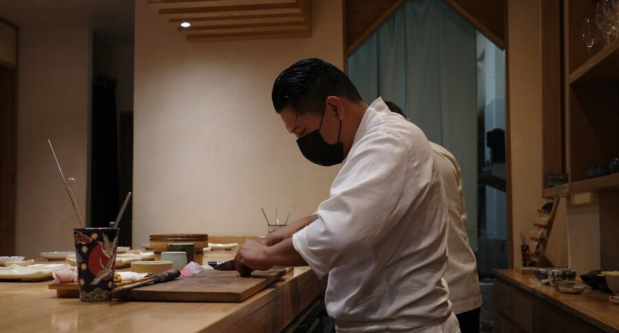Sushi chef slicing fish at a small counter in Tokyo