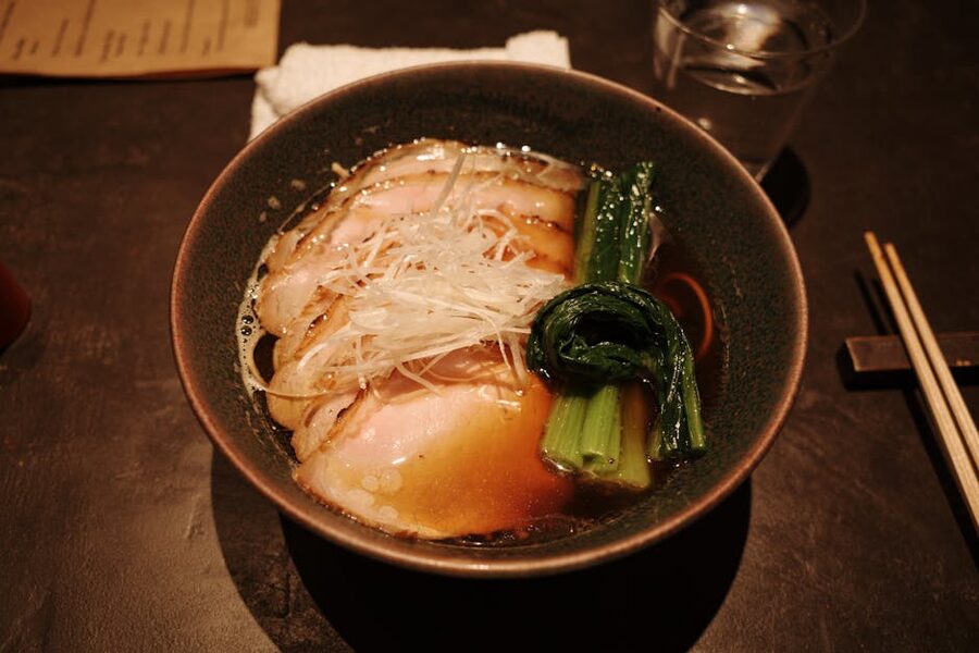 A bowl of Japanese ramen with pork slices and greens