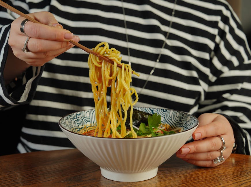Ramen noodles being lifted from the bowl with chopsticks