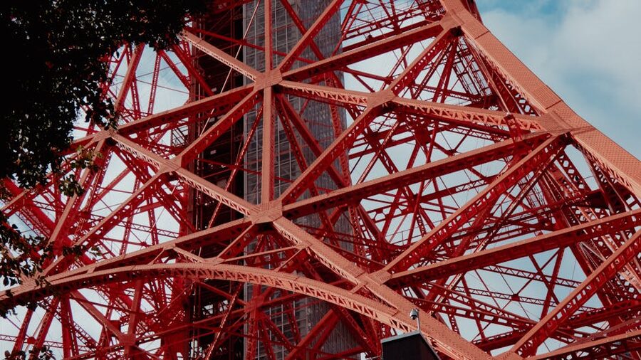 Close-up of Tokyo Tower's red and white lattice steel structure against a blue sky