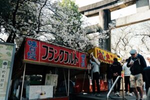 Stone lanterns and food stalls under cherry blossoms near Ueno Toshogu shrine, Ueno Park, Tokyo