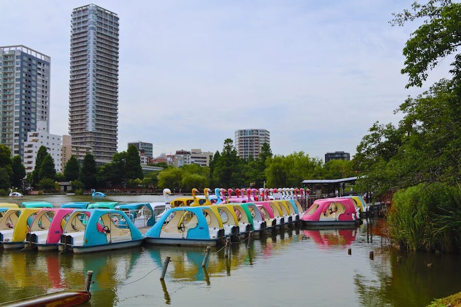 Colourful swan pedal boats docked on Shinobazu Pond with Tokyo cityscape behind, Ueno Park
