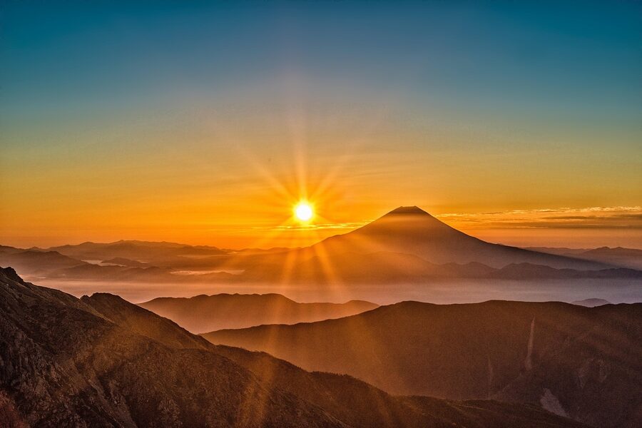 Mount Fuji at sunrise, snow on the summit, orange sky behind