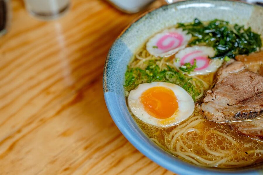 A bowl of Japanese ramen with soft-boiled egg, chashu pork, and spring onions