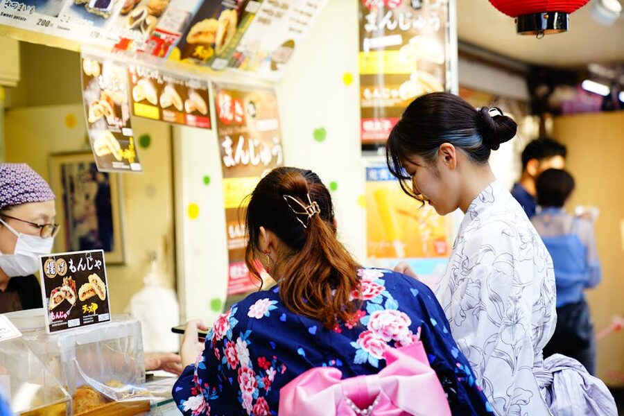 Women in yukatas at a Japanese summer festival food stall